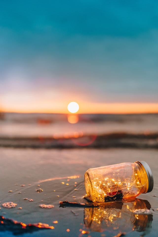 Bottle with fairy lights in a beach at dusk