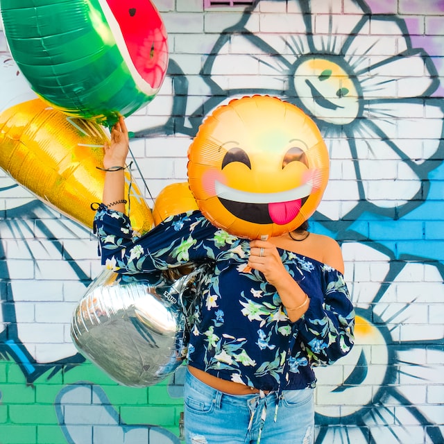 Woman with a smiley emoji ballon in front of her